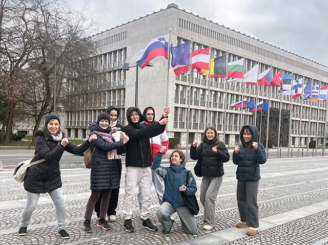 Fotografija prikazuje skupino dijakov na ploščadi pred slovenskim parlamentom. Eden od dijakov ima roke stegnjene v zrak, kot da bi v roki držal palico s slovensko zastavo, ki dejansko stoji v ozadju. Ostali imajo roke stisnjene v pesti, kot da bi bili pripravljeni na boj. Tako so uprizori prizor na temo "revolucija".